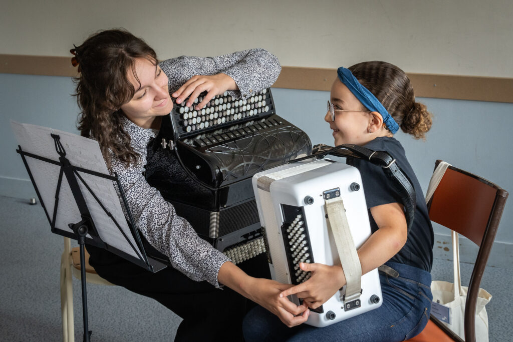 Une professeur d'accordéon explique à une jeune enfant comment fonctionne l'instrument.